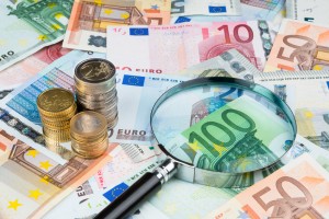 Billetes y monedas de euro con lupa que podría pertenecer a un grupo organizado de blanqueo de capitales