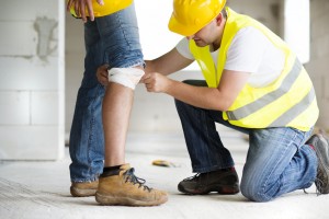 Un operario pone una protección a la rodilla de otro en una actuación de prevención de riesgos laborales