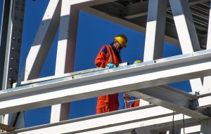 Un obrero en lo alto de una construcción aplicando el plan de accidentes laborales